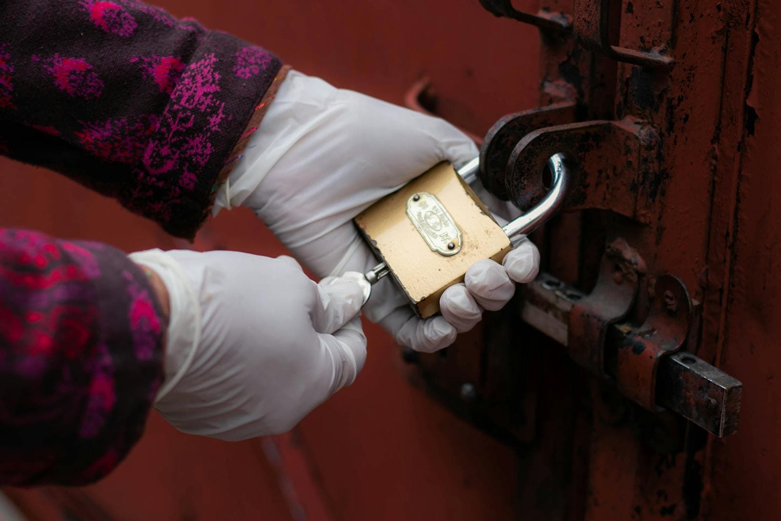 A gloved hand holding a gold padlock with a single key inserted, the visual metaphor for the access-control problem every company has and most do not audit until something goes wrong